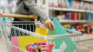 pessoa colocando materiais escolares em carrinho de compras