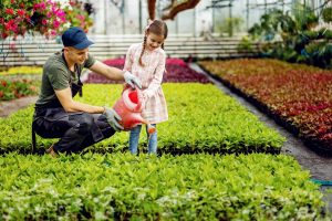 Jovem ensina menina a regar plantas (Foto: Freepik)