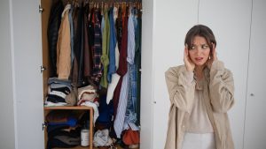 mulher preocupada com armário cheio de roupas