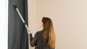 mulher passando aspirador em cortina