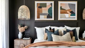 quarto com paredes escuras e quadros na cabecedeira