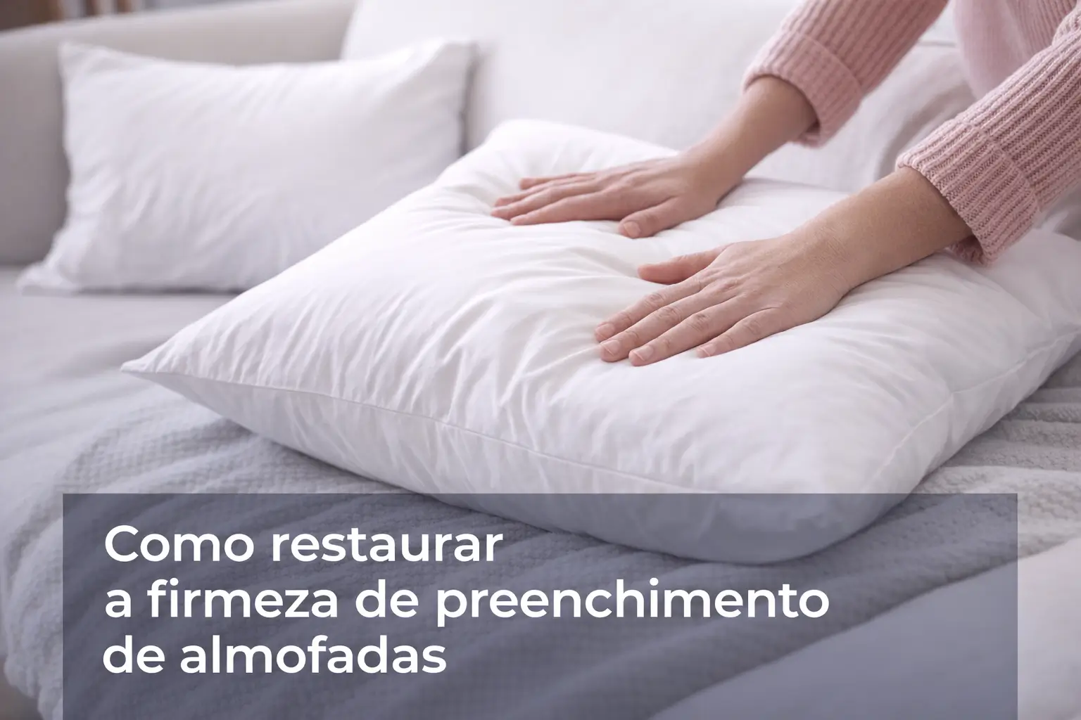 Mãos ajustando almofada branca em um sofá claro com manta ao fundo